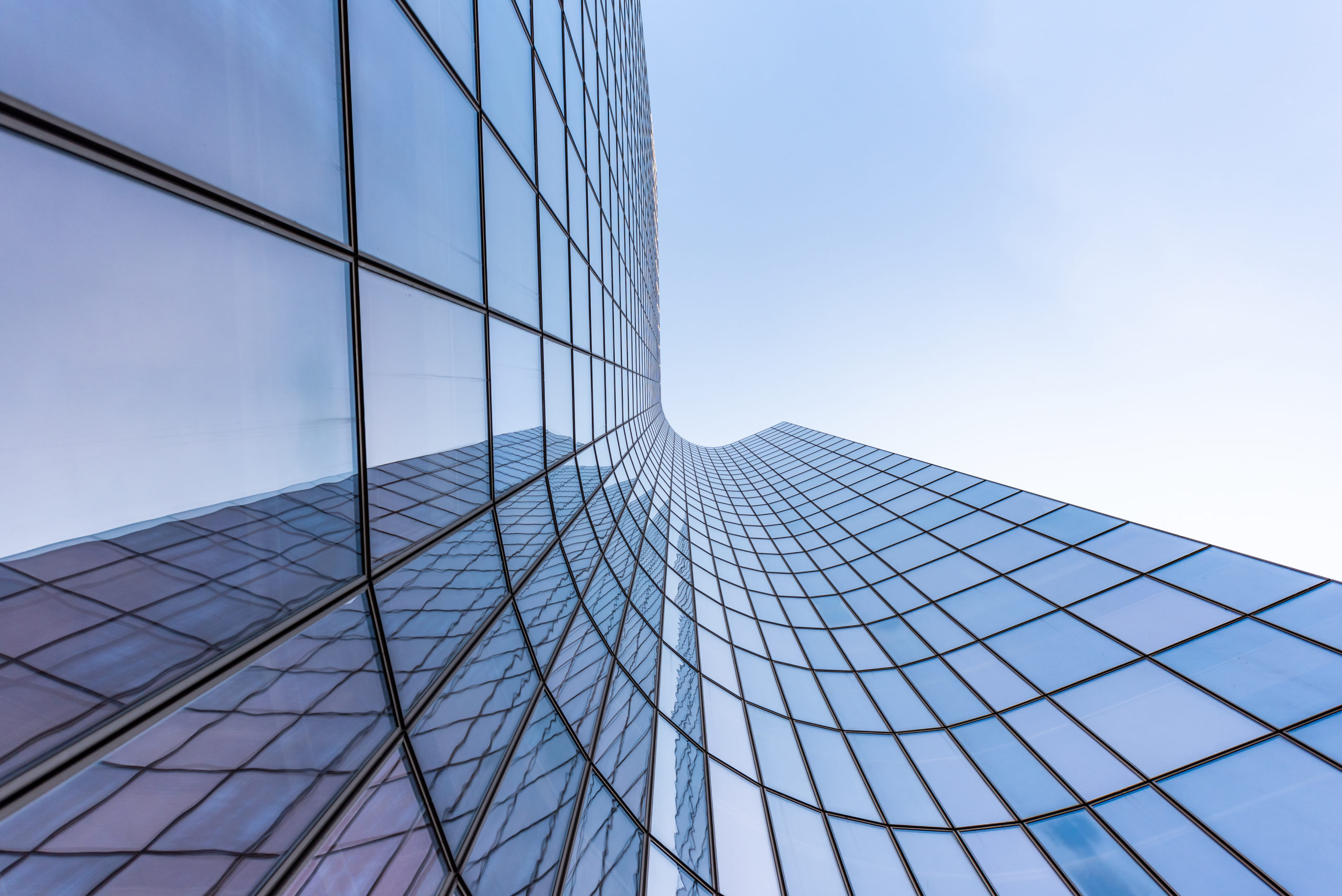 Reflets de la façade d'un gratte-ciel en verre incurvé bleu contre le ciel