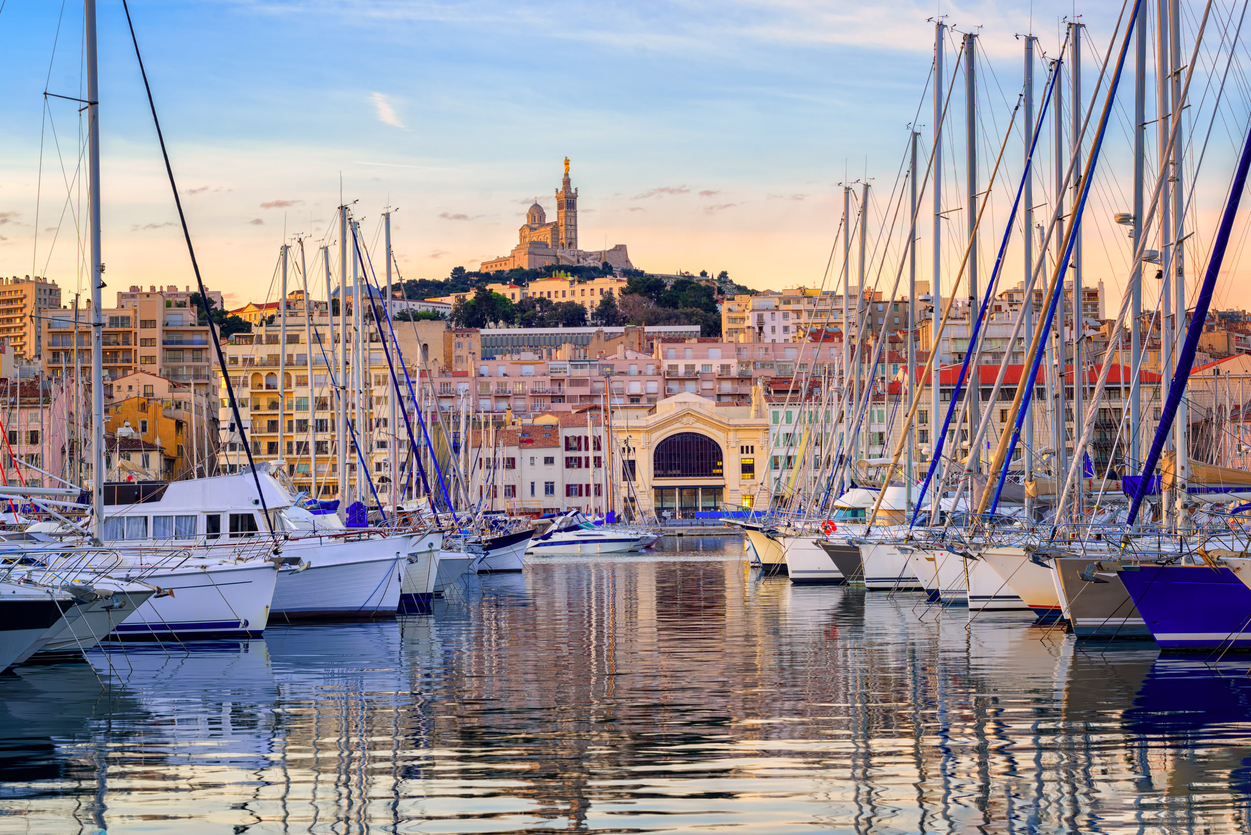 Yachts se reflétant dans l'eau calme du Vieux Port de Marseille sous la cathédrale de Notre Dame, France, au lever du soleil.